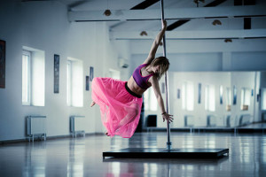 Dance performer dancing on a pole in a studio.